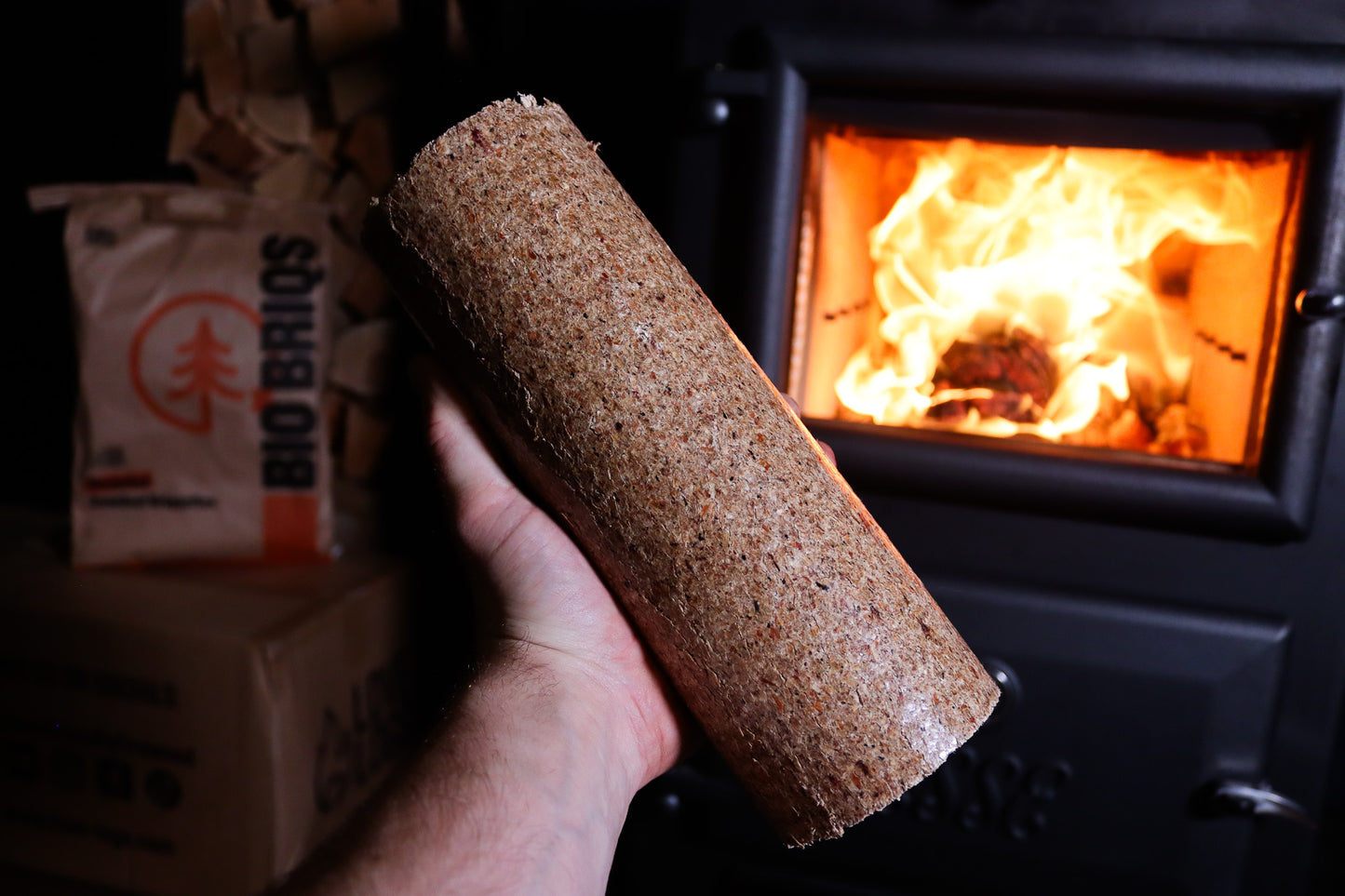 Bio Briqs firewood sawdust briquette in front of lit log burner
