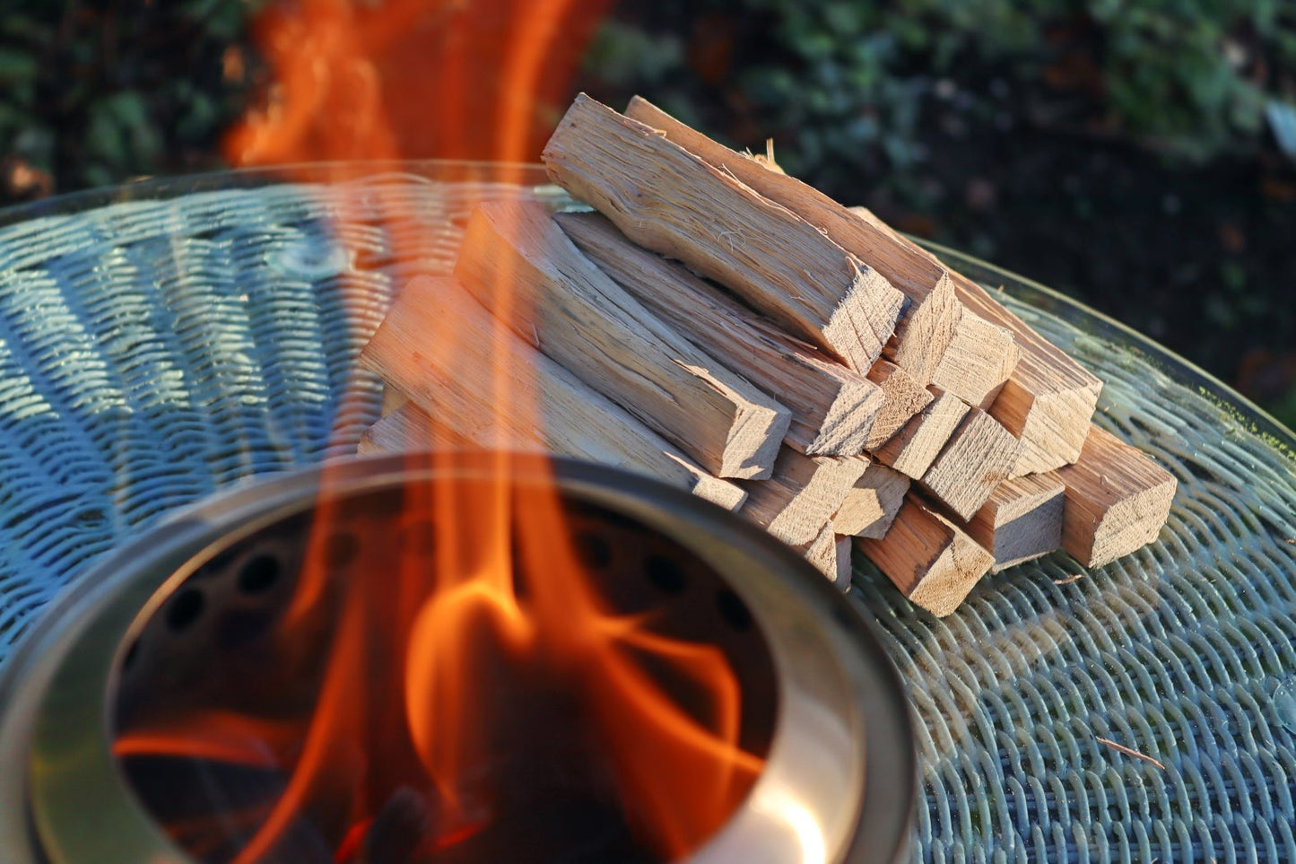 Love Logs Mini Fire Pit Wood burning cleanly in Mesa XL with wood stacked in the background