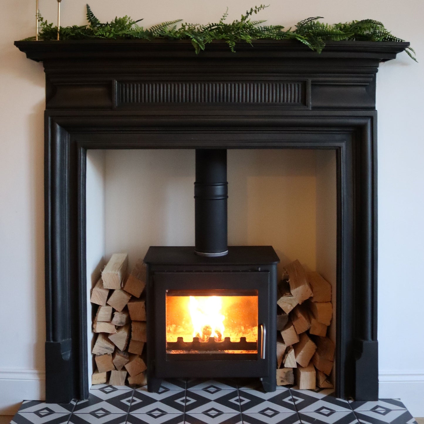 Log burner with firewood stacked around it and roaring fire inside