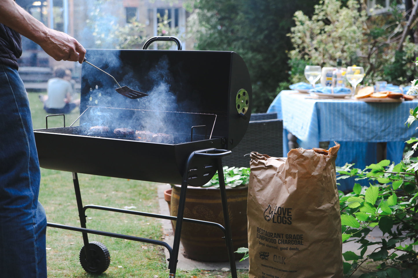 Person cooking burgers over charcoal in a light spring garden