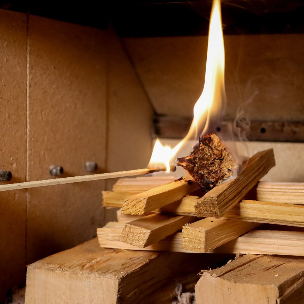 Love Logs natural firelighter being lit by a Love Logs extra long match